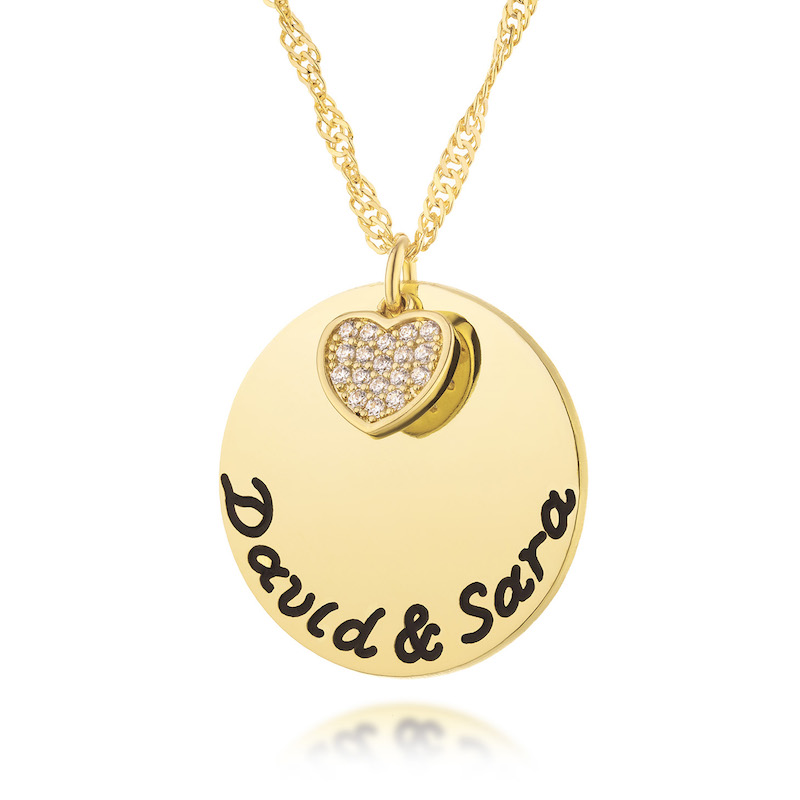 A round pendant for engraving is combined with a heart element studded with zircons