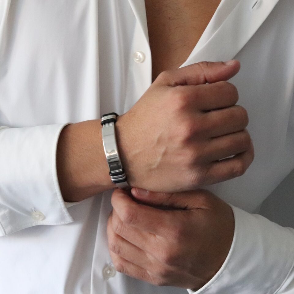 A bracelet for men with a strap in the form of a belt and a metal strip in the middle for engraving